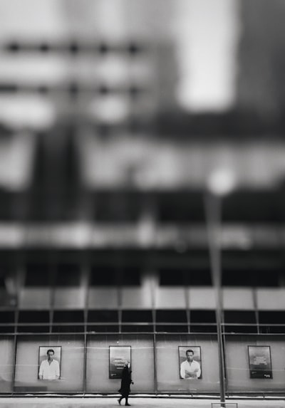 A black and white photo of a person standing in front of a building