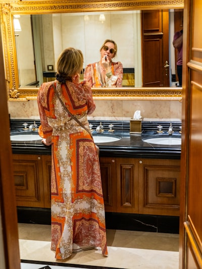 Woman in colorful dress framed by ornate mirror
