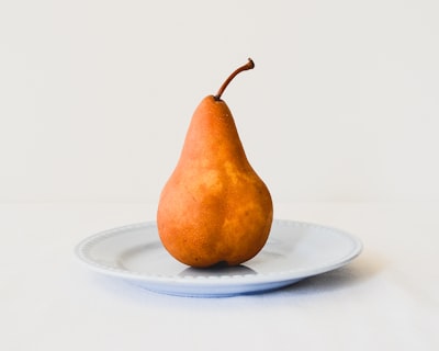 Orange pear on white ceramic plate