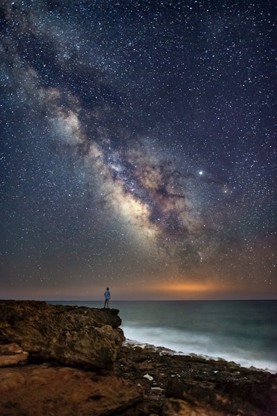Person standing on cliff during nighttime