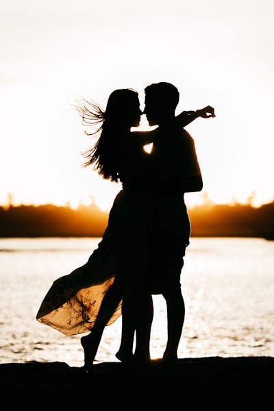 Silhouette of woman standing on beach during sunset