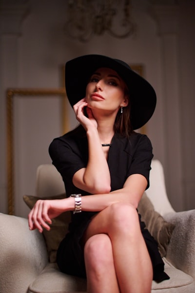 A woman sitting on a couch wearing a black hat