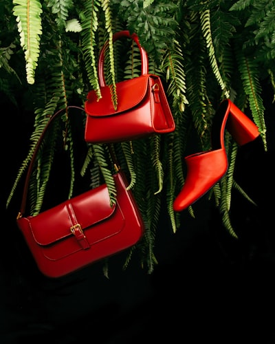 Red leather handbag on green pine tree
