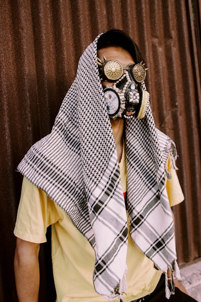 Fine Art portrait of a male model wearing strange mask and Steampunk glasses and a Palastenian Scarf.