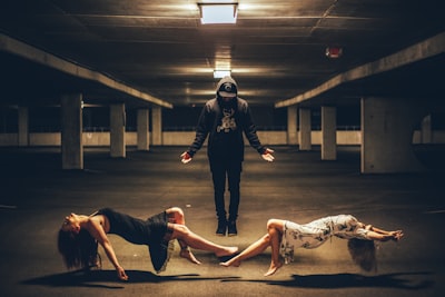Man standing between two women lying