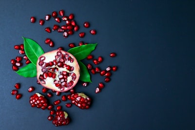 Fresh pomegranate with green leaves isolated on black background