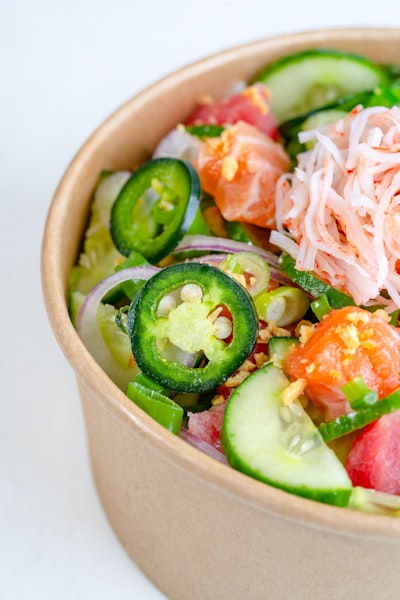 Sliced cucumber and tomato in brown ceramic bowl