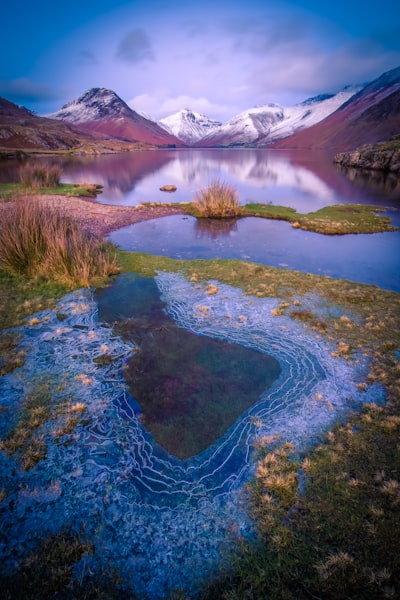 A body of water surrounded by mountains and grass