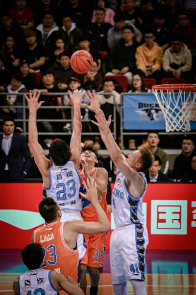 Men playing basketball in court surrounded by people