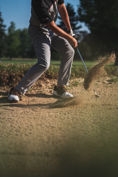 Person in black t-shirt and white pants holding golf club
