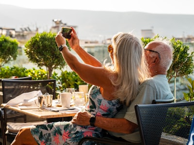 A man and woman sitting at a table taking a picture