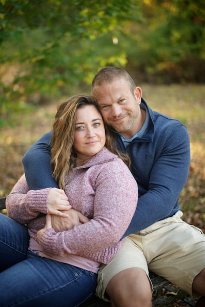 Man in blue sweater hugging woman in brown coat
