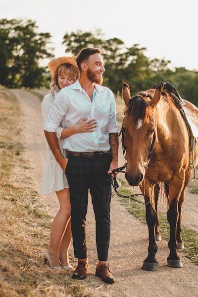 Woman in white button up shirt standing beside brown horse during daytime