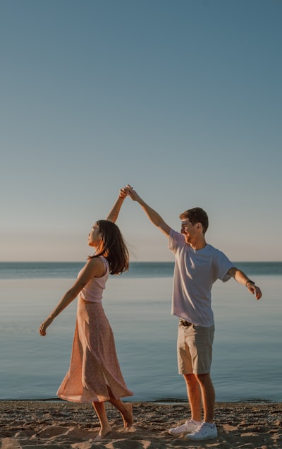 Man and woman holding hands while standing on seashore during daytime