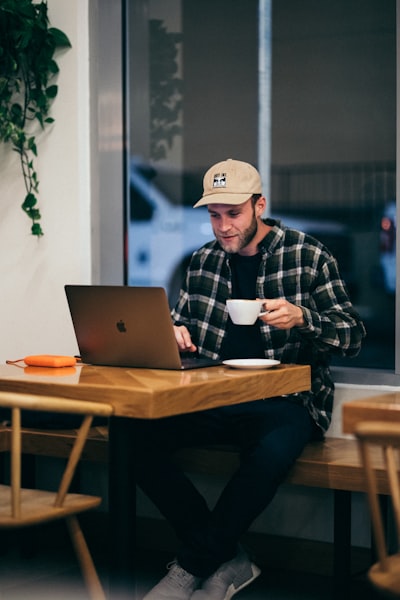 Man sitting while having coffee and using laptop
