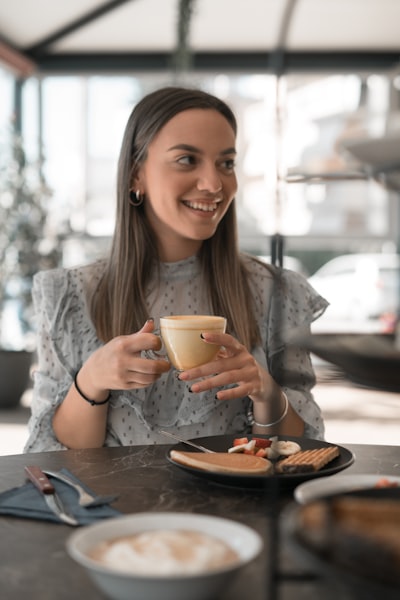 Woman in gray long sleeve shirt holding white ceramic mug