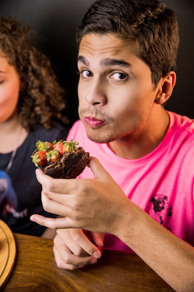 Boy in pink crew neck t-shirt holding chocolate cake