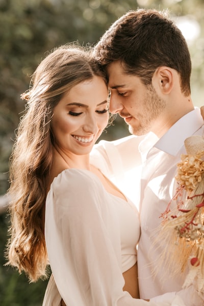 Man in white suit kissing woman in white dress