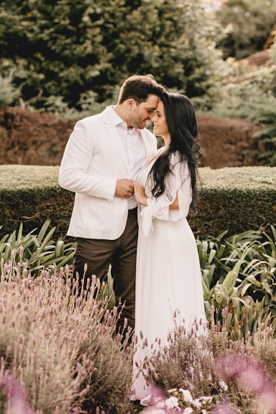Man in white suit kissing woman in white dress