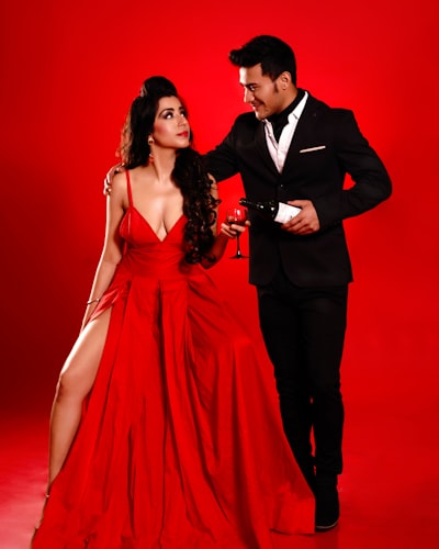 A man in a tuxedo standing next to a woman in a red dress