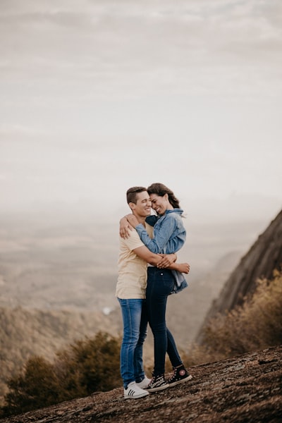 Man in blue denim jeans carrying woman in white long sleeve shirt