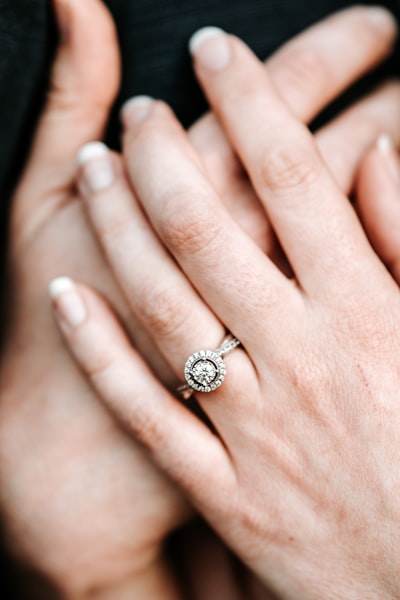 Close-up of diamond engagement ring on intertwined hands