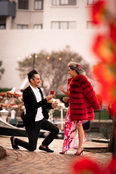 Man on one knee proposing with red ring box