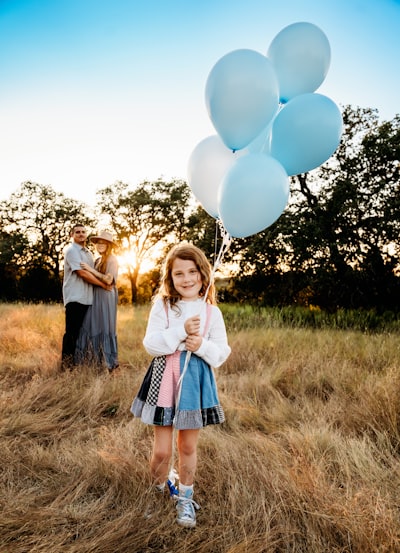 A little girl holding a bunch of white balloons