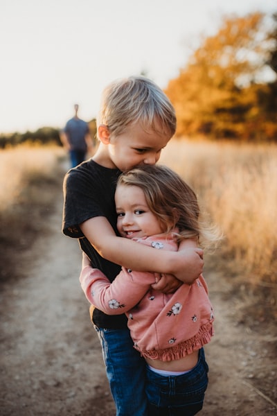 Boy in black t-shirt hugging girl in red and white polka dot dress