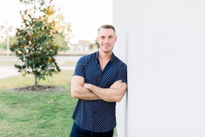 Alex Sanfilippo, the founder of PodPros, confidently leaning against a wall with arms crossed out on the lawn. Model Alex Sanfilippo, the founder of PodPros @ PodPros.com