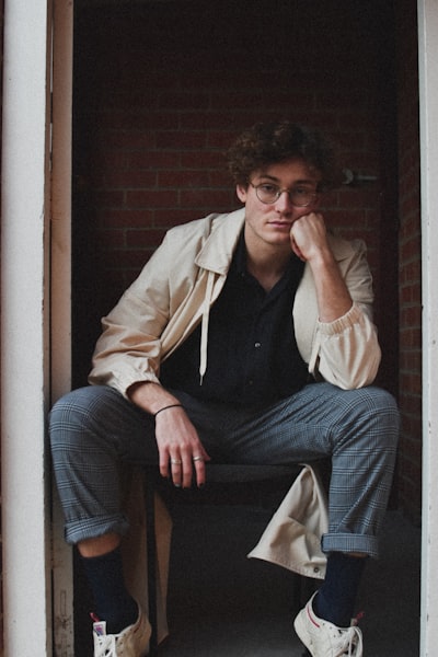 Man in brown jacket and blue denim jeans sitting on brown wooden chair