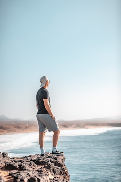 A man standing on top of a rock next to the ocean