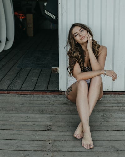 Woman in white sweater and black skirt sitting on concrete wall during daytime
