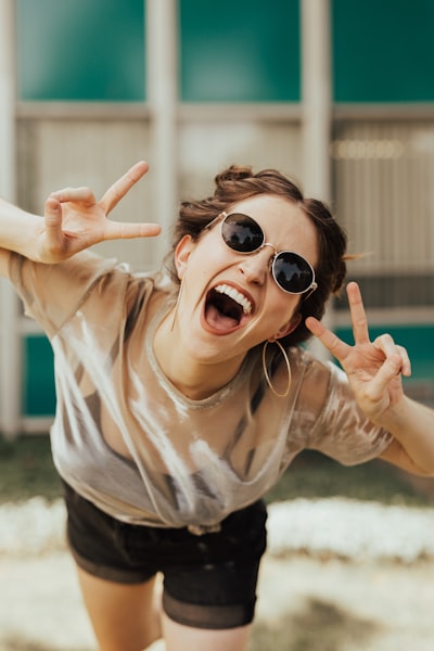 Playful woman with sunglasses showing peace signs