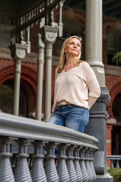 A woman leaning against a lamp post in a park