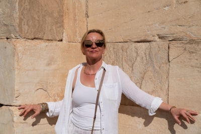 Woman with open arms against ancient stone wall