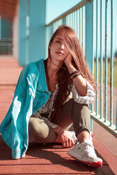 Woman in white spaghetti strap crop top and blue denim shorts standing beside railings during daytime