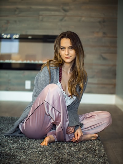 Young woman in pink pajamas seated on carpet