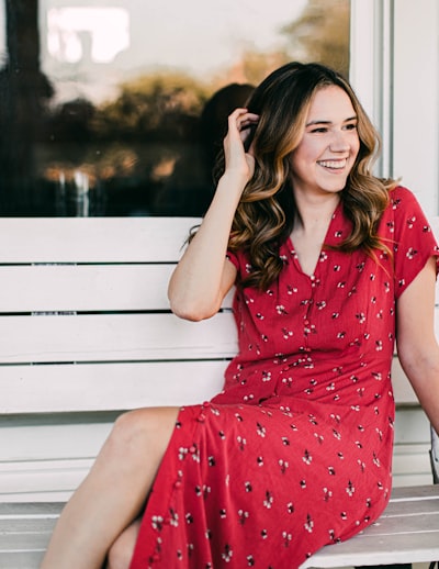 Smiling woman in red dress on white bench