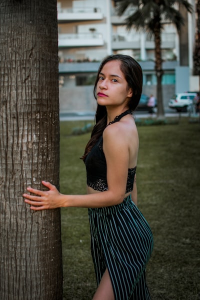 A woman leaning against a tree in a park